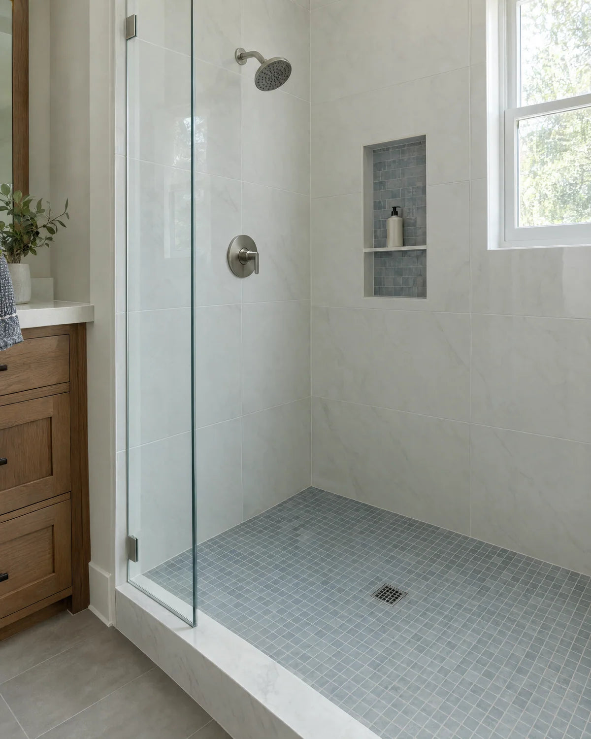 Porcelain tiled shower with a mosaic floor and glass panel