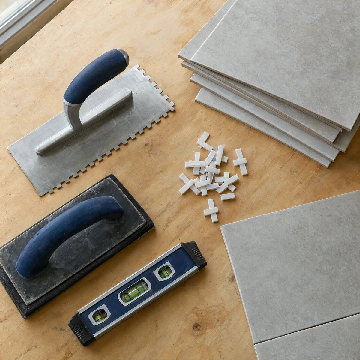 Trowel, spacers, level and tile samples ready for installation planning